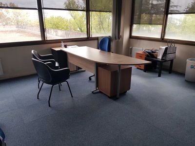 a desk and chairs in an empty room with large windows