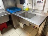 a sink in the middle of a kitchen with a trash can in the corner