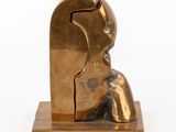 bronze sculpture of a woman sitting on a wooden base with a white background