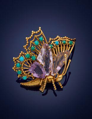 a close up of a butterfly broochle with green and purple stones