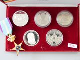 une boîte rouge sur laquelle se trouvent cinq pièces et une médaille