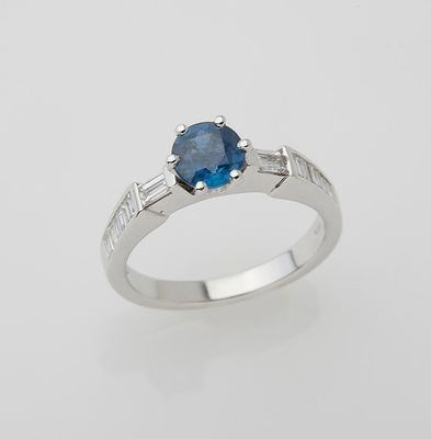 a close up of a ring with a blue stone on a white background