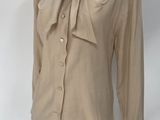 beige shirt with a bow on the neck on a mannequin stand