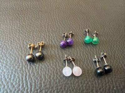 four pairs of earrings on a black leather surface