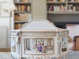 a miniature doll sitting in a miniature crib on a table
