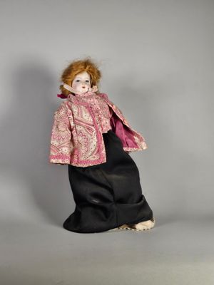 une image représentant une poupée à l'effigie d'une femme vêtue d'un manteau rose et d'une robe noire