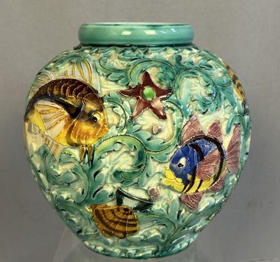 un vase vert orné de poissons, posé sur une table