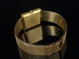 gold plated bracelet with a square clasp on a black background