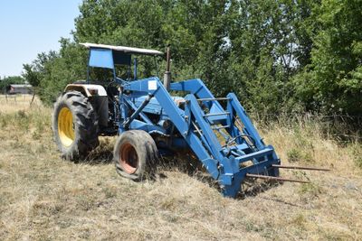 a blue tractor that is parked in the grass