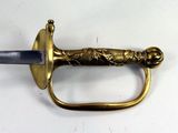 a gold colored sword with a black handle on a white surface
