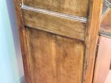 a tall wooden cabinet with a door on top of it