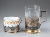 two cups with gold and silver designs on them sitting next to each other
