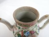 a small tea pot with a handle on a table