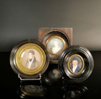 three miniature portraits of people are displayed on a black surface