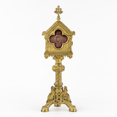 an image of a gold clock with a red face on a stand