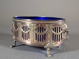 a silver and blue glass bowl on a stand on a gray surface