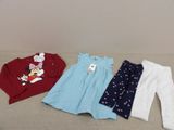 trois vêtements d'enfants posés sur un canapé dans une pièce