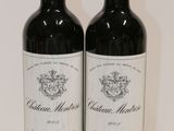 two bottles of red wine sitting on top of a white table