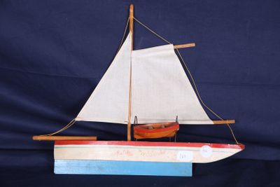 maquette en bois d'un voilier aux voiles blanches sur fond bleu