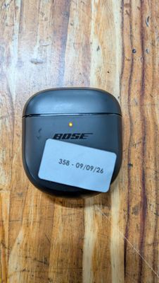 des AirPods noirs posés sur une table en bois sur laquelle est collée une étiquette