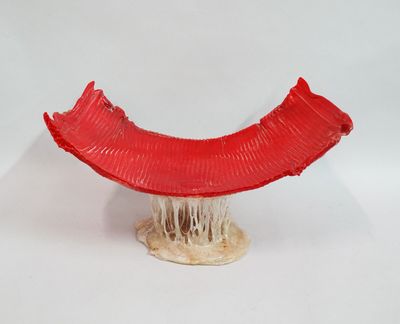 une sculpture rouge représentant une banane posée sur une surface blanche