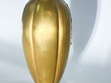 a gold vase sitting on a white surface with a shadow