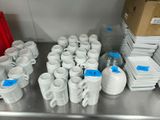 many cups and mugs sitting on a metal counter