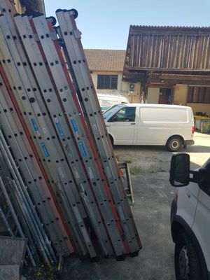 a white van parked in front of a building with a bunch of ladders on it