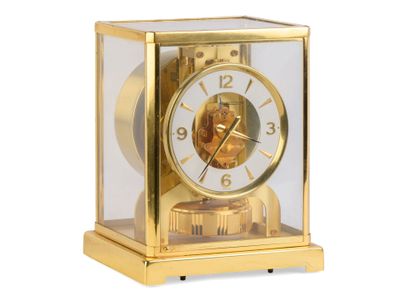 une horloge en or posée sur une surface blanche
