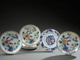 four plates with flowers and birds on them are sitting on a table
