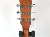 the headstock of an acoustic guitar on a stand against a white background