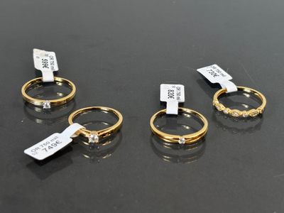 trois bagues en or munies d'étiquettes, posées sur une table