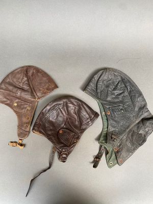 trois chapeaux en cuir empilés les uns sur les autres sur une table