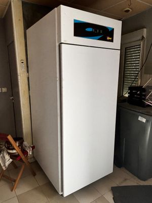 un réfrigérateur blanc dans une cuisine, à côté d'un lave-linge et d'un sèche-linge