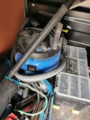 a blue and black vacuum in the middle of a pile of assorted items