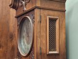 a wooden grandfather clock sitting on the floor next to a cabinet