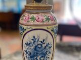 un vase posé sur une table, avec une horloge en arrière-plan