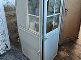 une armoire bleue avec une porte vitrée, dans un coin de la pièce