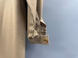 une chemise beige suspendue à un cintre devant un mur bleu