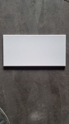 white tile on the wall of a bathroom with a toilet and a sink