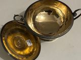 pair of silver plated bowls with handles on a white surface