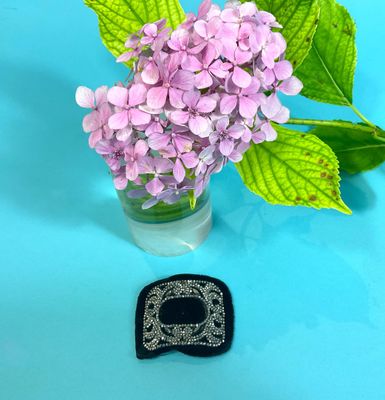 purple flowers in a vase with a black broocher next to it