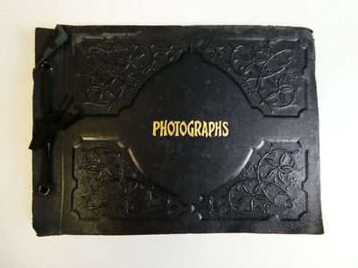 an old black book with gold lettering on it sitting on a table