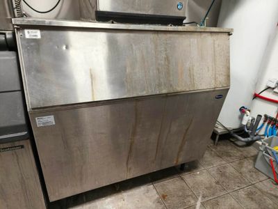 a stainless steel ice maker in a kitchen next to a refrigerator