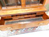 a wooden display case with glass doors and drawers