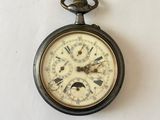 une montre de poche accrochée au mur, sur laquelle figurent des chiffres romains