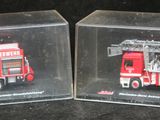 deux boîtes transparentes contenant un camion de pompiers rouge et un camion de pompiers blanc