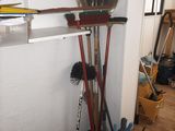 brooms, brooms, and other tools are on a shelf in a room