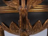 a gold and black vase on a stand with a bird on it