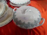 many plates and bowls on a table with a red table cloth